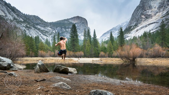 A shirtless young man jumping inside the ice-cold water of Mirror Lakes at Yosemite National Park, California, USA.