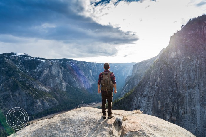 A young adult whit his backpack contemplating the view before him, at Yosemite National Park, California, USA.